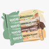 Produktový snímek představující čtyři veganské energetické tyčinky Hanso Apfelstrudel Chocolate Chip Double Choc a Salted Peanut v pastelových barevných obalech s viditelným složením a BIO etiketou.
