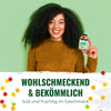 Product photography: A smiling woman with big, curly hair holds a bottle of hemp gummy bears with fruity, colorful bears in her hand against a light green background and wears a mustard yellow top.
