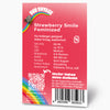 Bud Voyage Grafikdesign: Produktbeschreibung für Strawberry Smile feminisierte Hanfsamen mit Regenbogen, QR-Code und detaillierten Angaben zu THC-Gehalt, Blütezeit und fruchtigem Erdbeer-Zitrus-Aroma auf rosafarbenem Hintergrund
