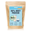 Product photo by Hanso: A brown package with 80% whey protein, organic seal, a glass of milkshake and measuring spoon, as well as blue and green design elements
