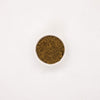 Photograph: A white bowl with a brown, grainy powder that looks like spice on a white background
