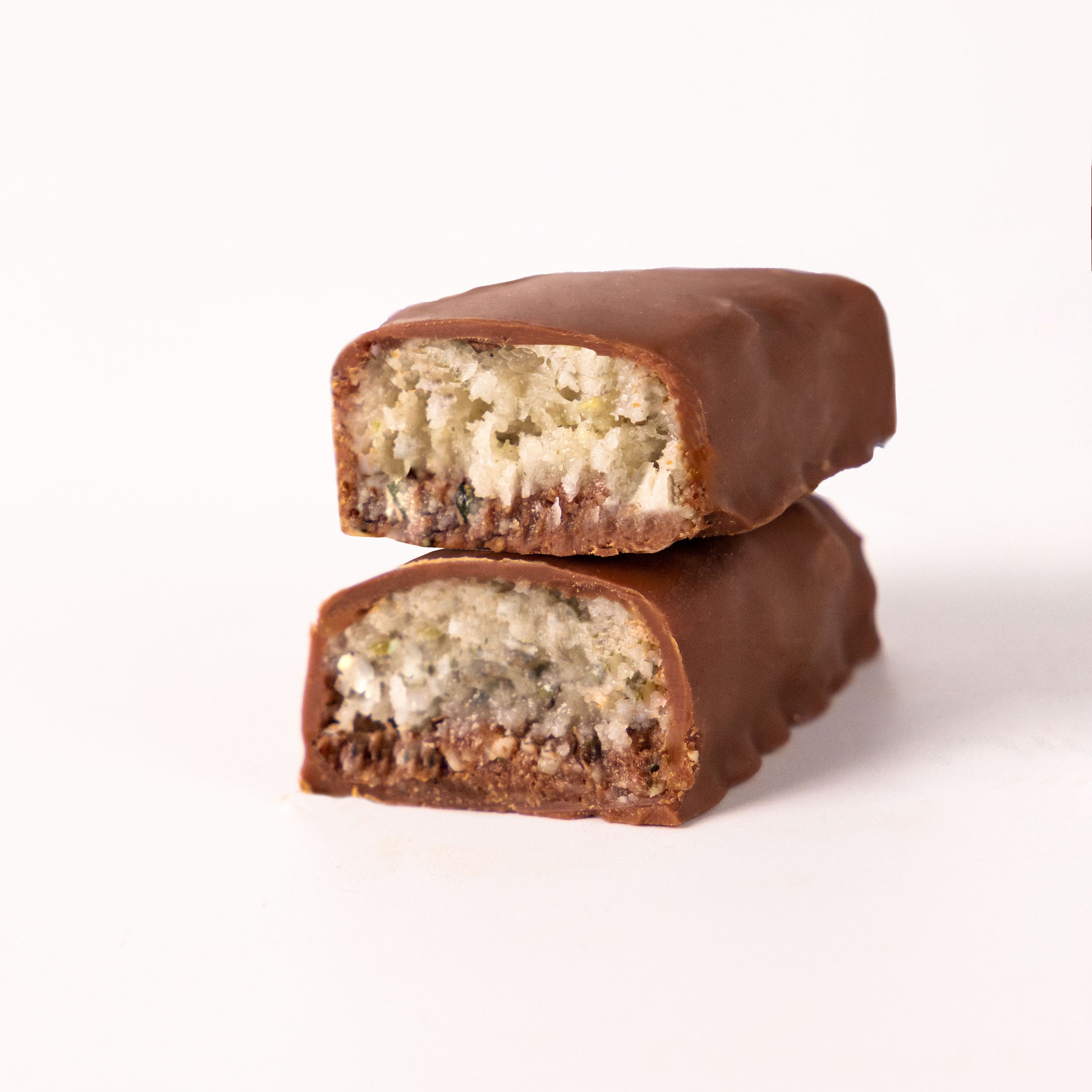 Photography: Two broken chocolate bars with coconut filling on a white background show the brown chocolate, the white coconut and the dark chocolate base