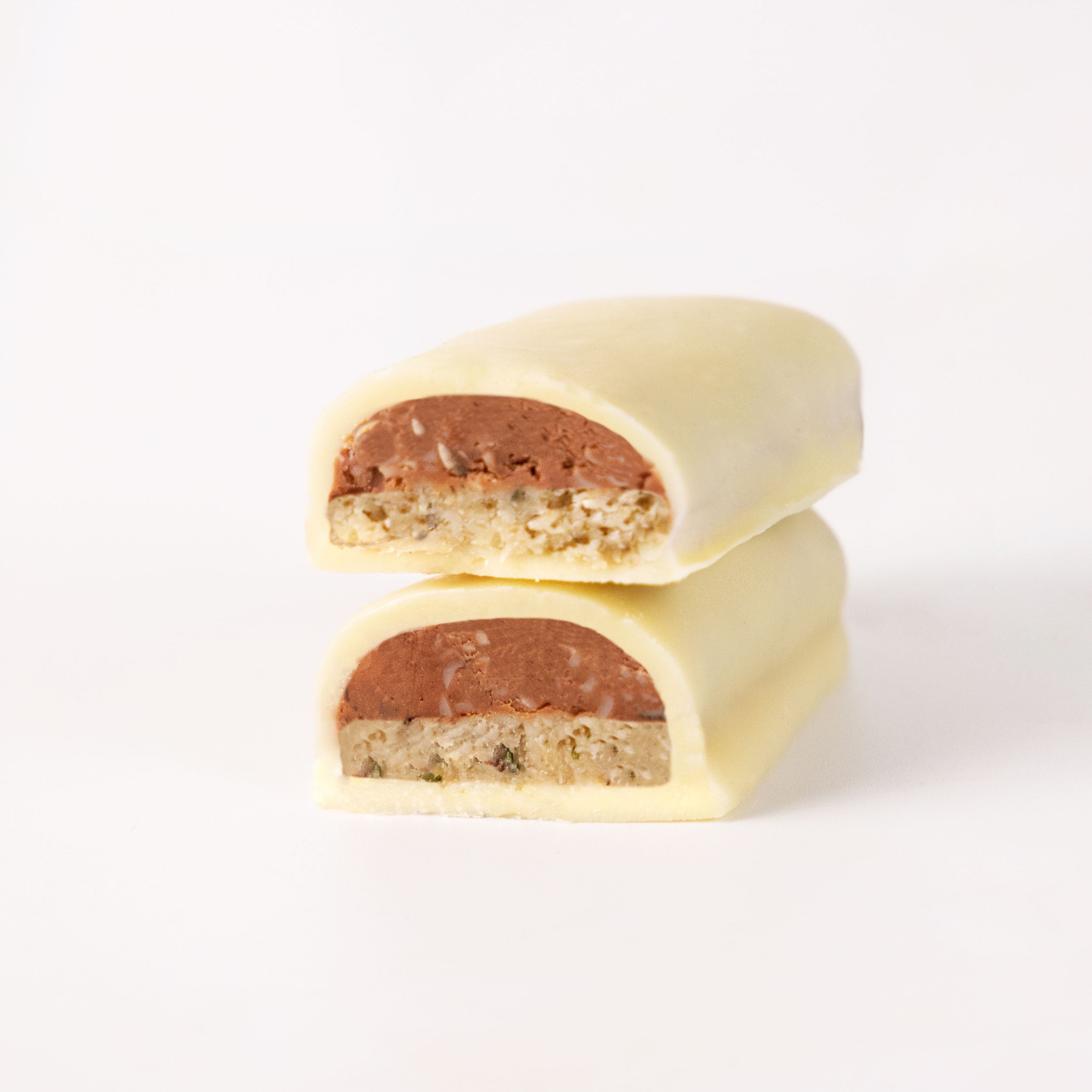 Photography: Two halved chocolate bars with white chocolate, brown filling and crunchy layer of cereals and nuts on a white background
